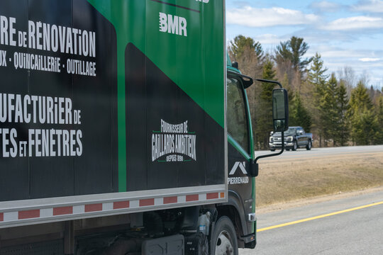 Quebec, Canada, 24 April 2026 : A BMR delivery truck with "Pierrenaud" branding drives on a highway past a forest.