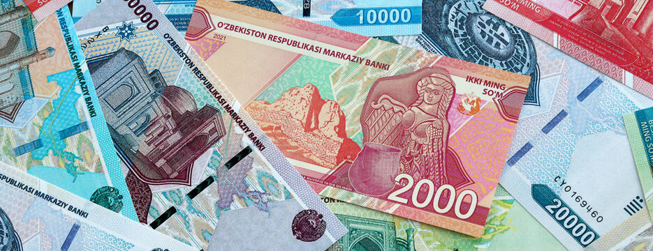 Uzbekistani som money banknotes pile on table. Uzbekistan bills of UZS currency close up