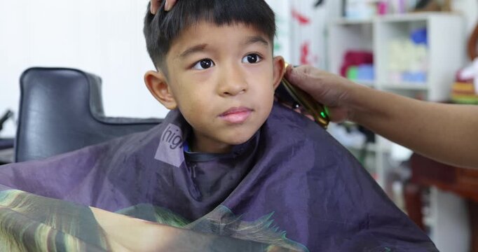 Little asian school boy hair cut in man barber shop beauty fashion