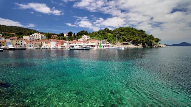 Idyllic Rovenska harbor in Mali Losinj, Croatia showing waterfront buildings and their reflections shimmering on the calm evening water of Losinj Island in Croatia