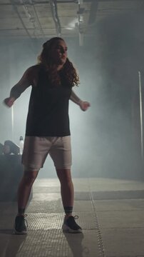 Vertical video of young Caucasian woman warming up and shadow boxing in boxing gym. Clip is ideal for fitness brand commercials, athletic motivation videos, or gym promotional campaigns