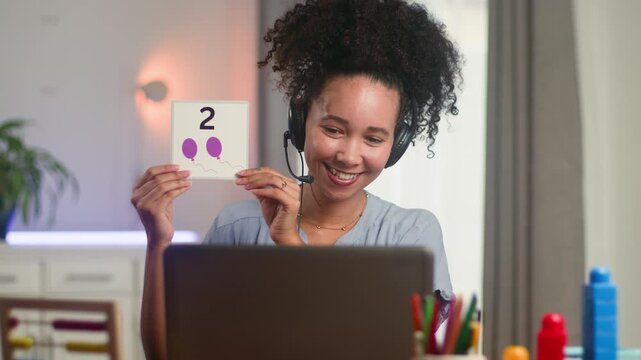 Smiling Black Woman Online Teacher Demonstrates Math to Primary School Students with Flashcards During Remote Learning