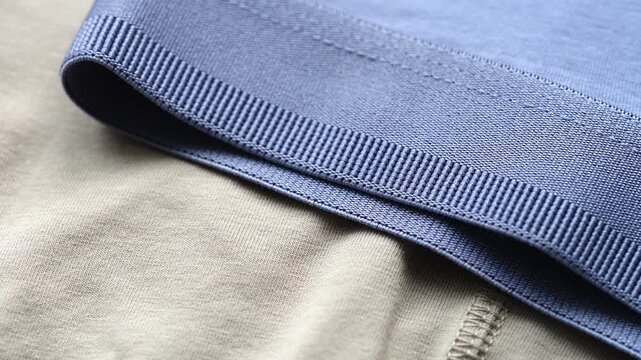 A close-up of beige and blue mens jersey underwear garments with elastic waistbands.