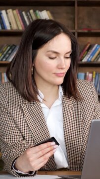 Professional woman holding a credit card and using a laptop for online payment. A happy customer making a secure purchase on an e commerce website while enjoying convenient internet banking