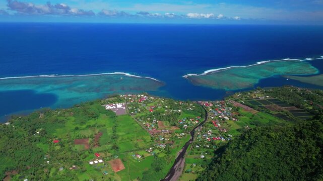 Aerial view sunny morning town of Teahupo'o village End of the Road Tahiti French Polynesia drone neighborhood buildings Teahupo'o wave lagoon surfing Passe Havea coral reef Vaiau River forward pan up