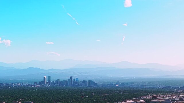Front Range downtown cityscape city of Denver skyscrapers buildings Aerial drone view Colorado cars highway foothills Rocky Mountains layers summer spring haze clear blue skies morning pan left