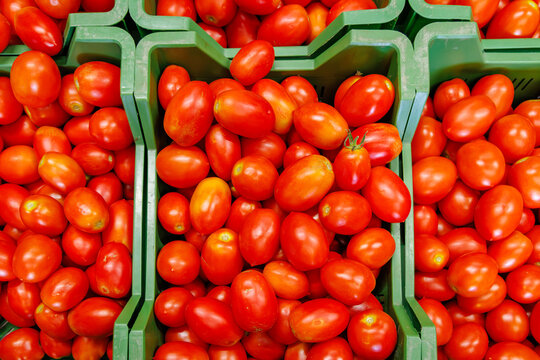 Tomatoes in green baskets at a market are ready for buyers during daylight hours