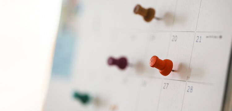 Focus on calendar grid with colorful thumbtacks.