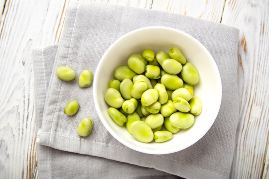 Fresh fava beans in a bowl on a grey napkin