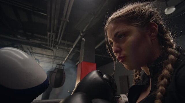 Two young Caucasian female boxers wearing gloves facing each other in boxing ring, preparing for fight. Ideal for fitness brand advertisements and female empowerment campaigns