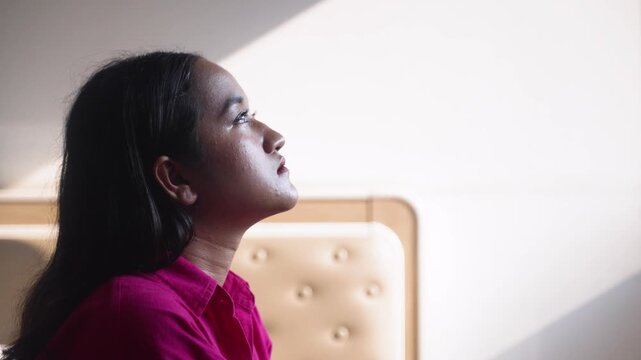 Young Asian Woman Taking Deep Breath Relief and Meditating in Bedroom Light