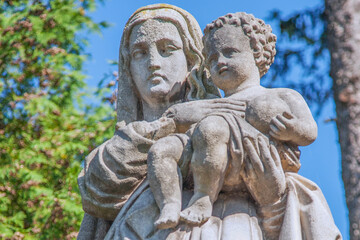 Fototapeta premium Stone statue of the Virgin Mary holding the Christ Child, symbolizing maternal love, divine protection, compassion, hope, and the sacred bond between Mother and Son in Christian faith.