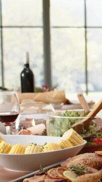 Vertical video: Reaching hand in grey sweater steadying glass serving salad by window for sharing