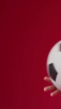 Vertical video: On ball entry pro in red jersey tossing, balancing soccer ball in studio, training