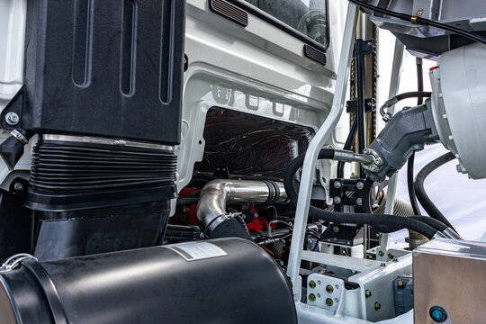 Semi truck chassis engine air intake duct behind white cabin. Commercial vehicle tractor rear frame section with exhaust pipe manifold and long haul transport machinery engineering details.