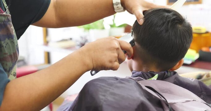 Little school asian boy enjoy hair cut barber shop service fashion concept