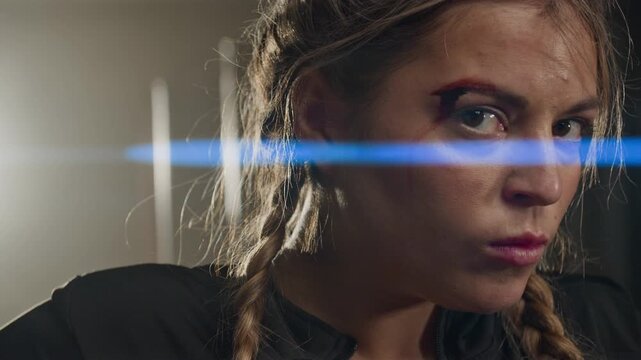 Portrait of young Caucasian woman with facial injury turning to look at camera with intense gaze. Clip is ideal for sports motivation, martial arts branding, or cinematic drama promos