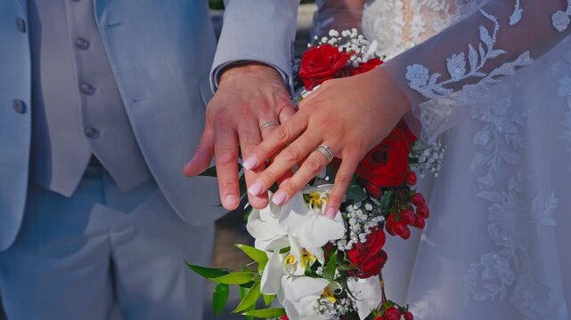 Bride and Groom Showing Wedding Rings over Elegant Bridal Bouquet