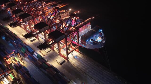 Unloading large cargo containers seaport. Loading freight sea port. Top aerial drone view. Lot big boxes rows, ship delivery ocean harbor. Shipping night. Goods export import. Industrial Marine dock.