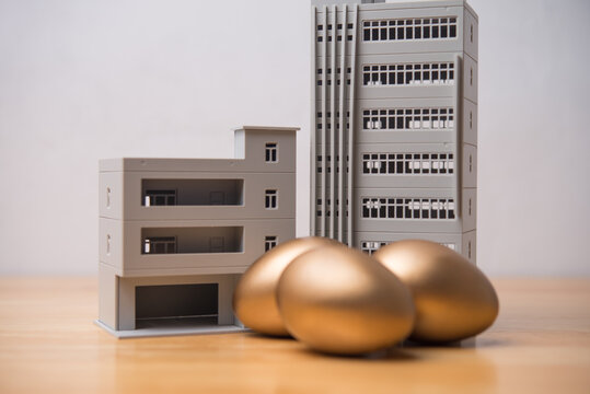 Commercial buildings and gold eggs on table. Dividend yield, returns or passive income from real estate investment trust (REIT), commercial real estate investment in stock market and so on concept.