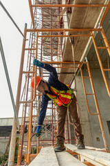 Construction Worker on Scaffolding  A construction worker in safety gear performs tasks on a scaffolding at a building site, demonstrating diligence and hard work in a high-rise environment. © Chanchai