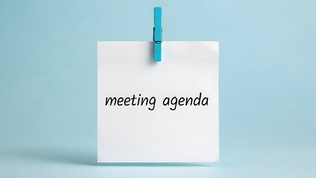White note paper with meeting agenda text hanging on a blue background