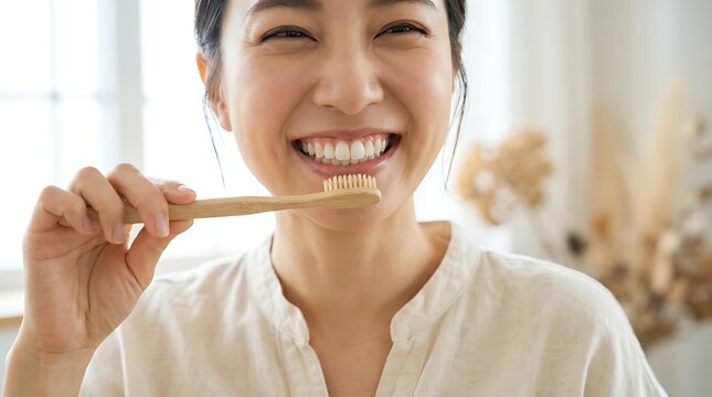 Smiling asian woman brushing teeth with sustainable bamboo toothbrush for daily oral hygiene routine