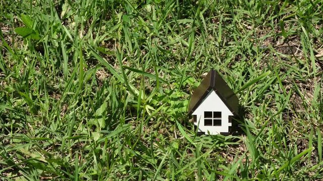 Small house model on green grass. Ecological countryside construction and real estate, mortgage, home loan, rural property concept