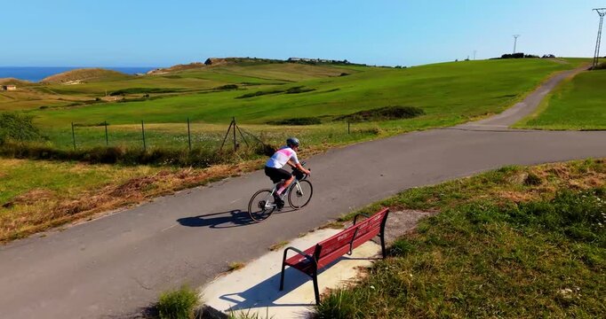 Active male cyclist riding professional bike on rural road. Male athlete riding sports bicycle on a narrow paved path in countryside.