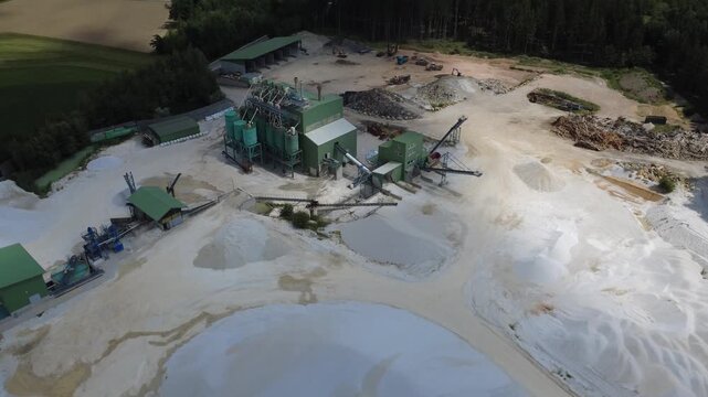 Aerial orbit over a gravel and sand quarry processing plant with shifting cloud shadows