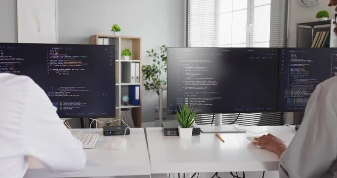 Developers programmers coding software as teamwork in office. Engineers collaborate at PCs reviewing code on screens and fixing bugs in collaboration. Teamwork in agile software development.