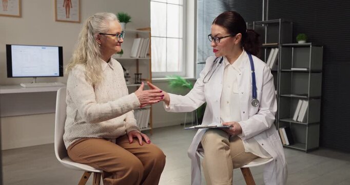 Doctor and patient senior woman in consultation. At the clinic the doctor explains diagnosis and treatment, reviewing results on a tablet. Healthcare guidance for informed patient decisions.