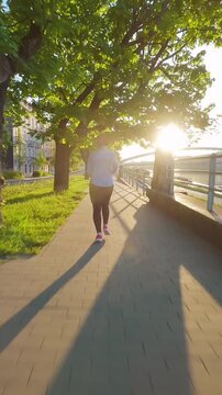 Caucasian woman runs along the embankment. Unusual view, filmed on FPV drone.