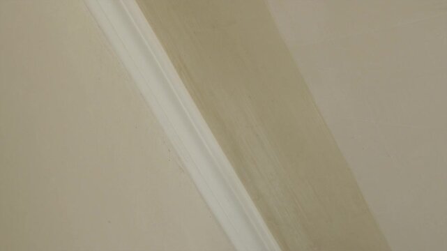 Close up of applying primer brush coat to wall and ceiling joint