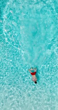 Aerial view as a man dives into the pool and swims. Slow motion