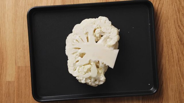 Olive oil brushes over cauliflower before roasting in oven. Roasted cauliflower is healthy, low calorie vegetable full of nutrients. Cauliflower works well as vegetarian side dish or diet meal.