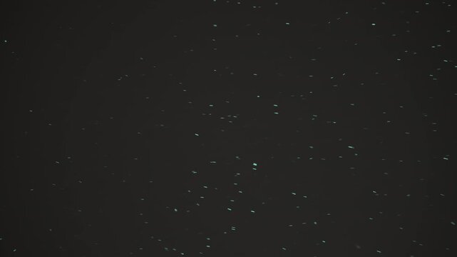 Green glowing particles and sparkling embers drift across dark empty space, creating a floating, starry effect
