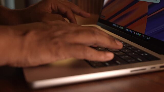 Hands Typing on Laptop Keyboard in Warm Cosy Lighted Room.