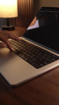 Hands Typing on Laptop Keyboard in Warm Cozy Lighted Room.
