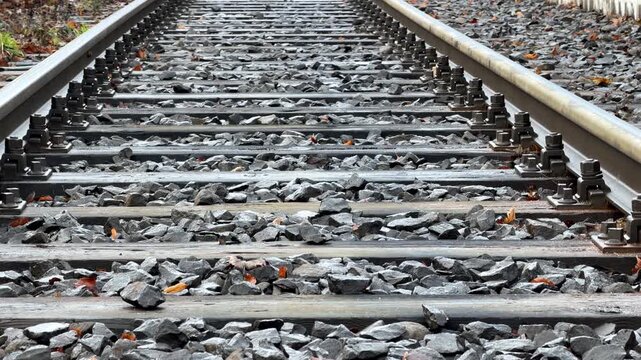 Railway tracks stretching into the distance with gravel ballast and wooden ties in a perspective view, symbolizing a journey, industrial travel, or the transition toward new goals