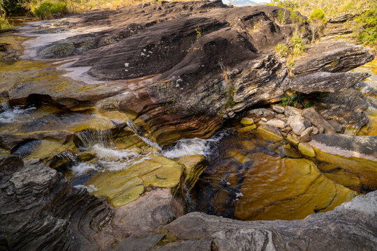 Clear river flowing over layered rock formations and quartzite stone beds in Ibitipoca, Minas Gerais, Brazil