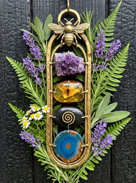Intricate golden frame with bee sculpture and natural gemstones surrounded by flowers