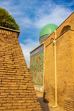 A narrow passage between the walls in the Shahi-Zinda necropolis ensemble in Samarkand, Uzbekistan. Brick walls decorated with blue geometric ornament.