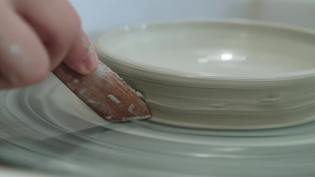 Ceramic plate processing process. Using stack on potters wheel to moderate and decorate pottery. Tool is used to remove excess clay at different stages of pottery processing.