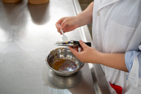 Crop View of Quality Control Technician Placing Caramel Sample on Refractometer in Food Laboratory