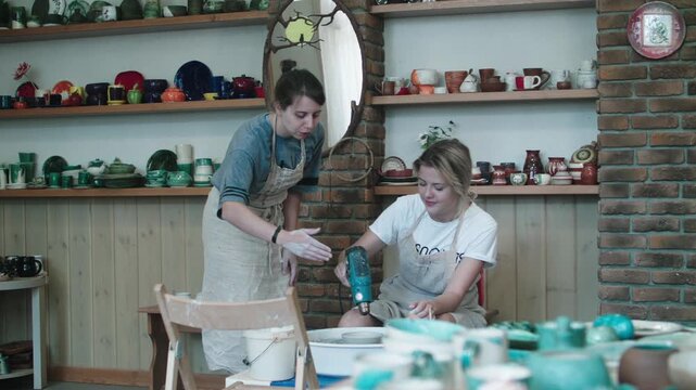 Master class in manufacture of clay products. Process of drying bucket with fishtail handle on potters wheel with special dryer. Handmade work