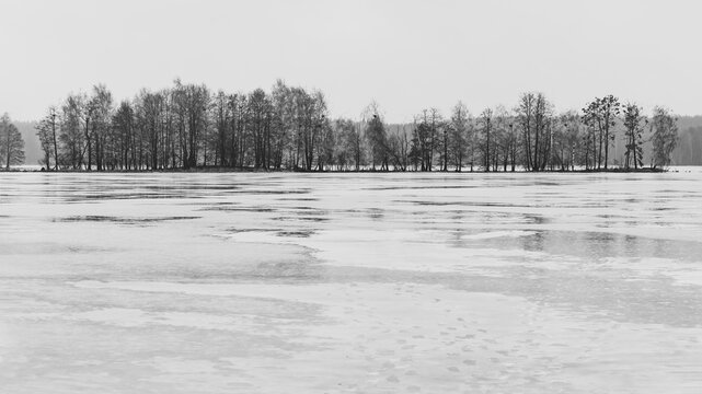Winter landscape with bad rainy weather in Belarus. A small island on an ice-covered lake.