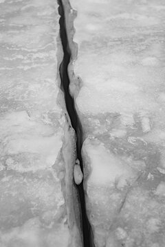Black and White Close Up of Deep Crack in Frozen Ice Surface