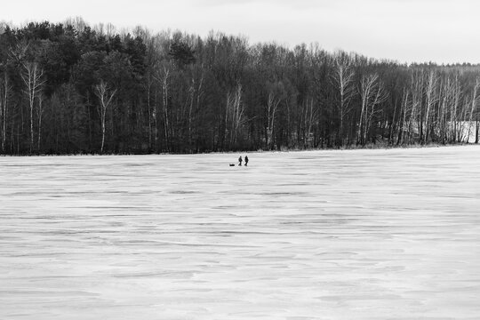 Dense Dark Forest Background Behind Two People on Frozen Winter Lake