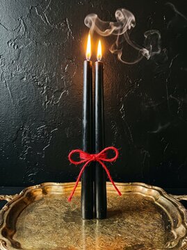 Sophisticated display of two glowing black candles with wisps of smoke on a shiny silver tray